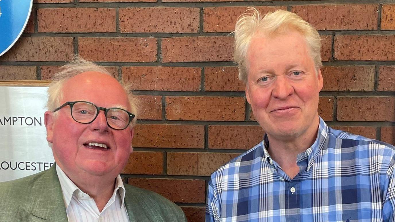 Two men looking at the camera. Earl Spencer (right) is wearing a blue, checked shirt; James Miller (left) has a white shirt and green jacket