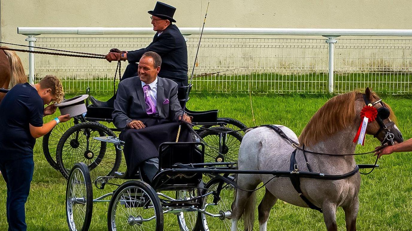 Two men on horse and carriage wearing formal wear