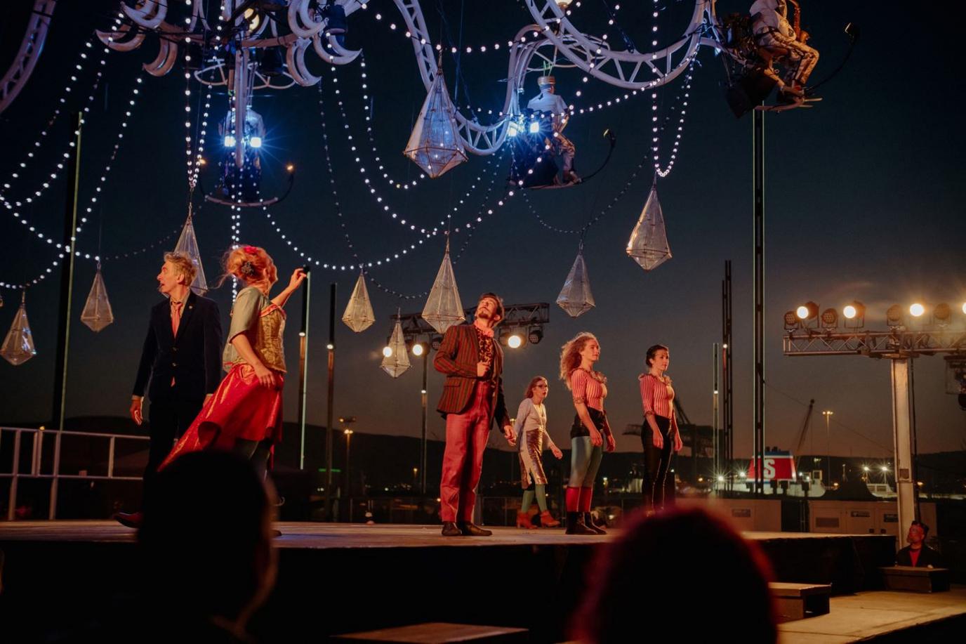 Performers on stage below the chandelier