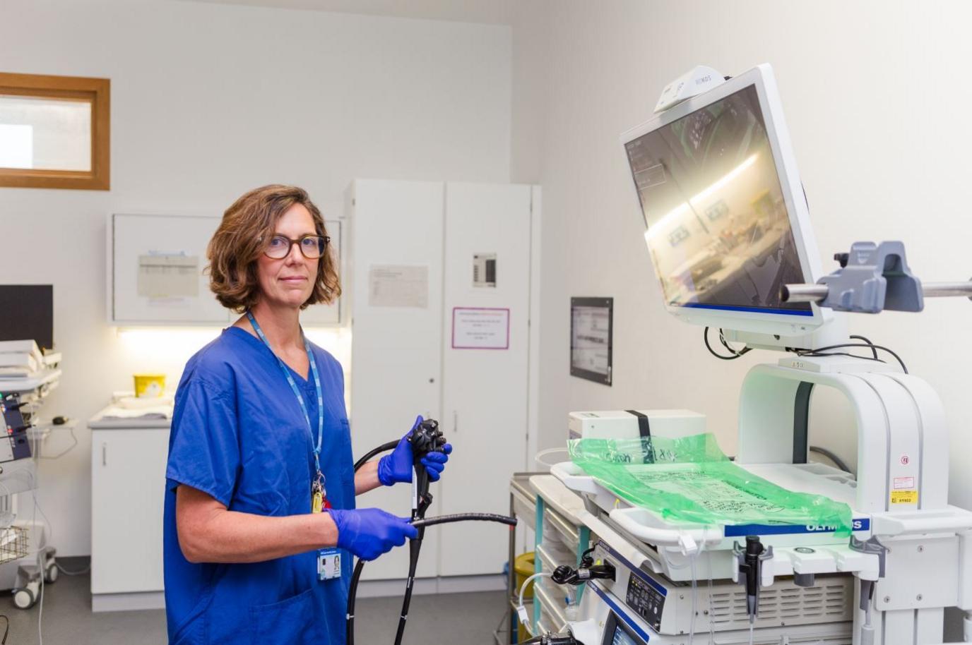 A doctor wearing blue scrubs standing in an operating theatre