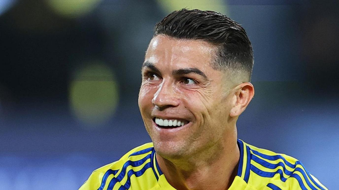 Cristiano Ronaldo smiling while wearing Al-Nassr's yellow and blue kit
