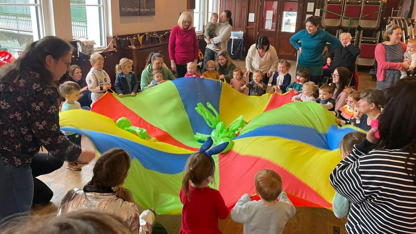 Singing Jo and Co session with children in a circle waving a large flag