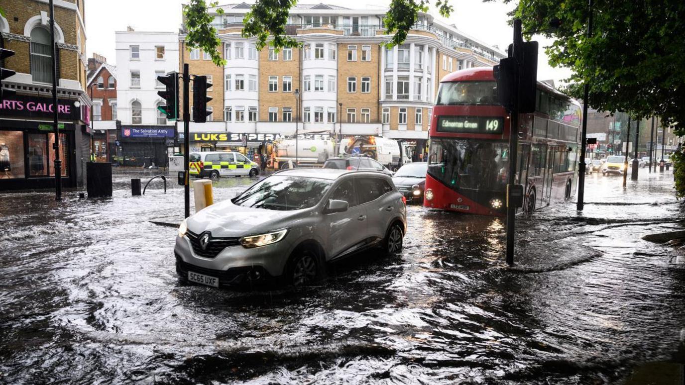 A photo of traffic driving through flooded roads