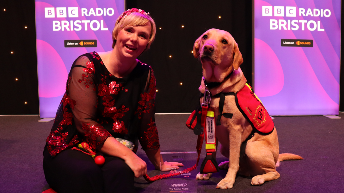 A dog and its owner on a stage with a prize.