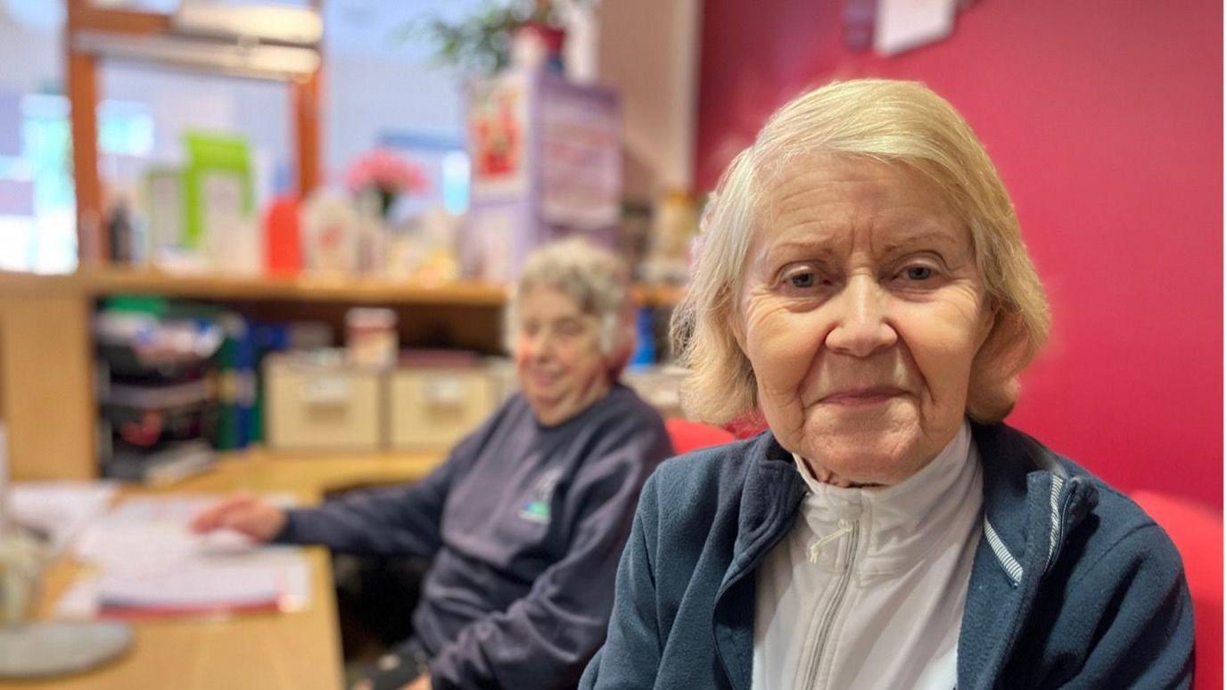 Diana Lewis looking into the camera sat with another woman 