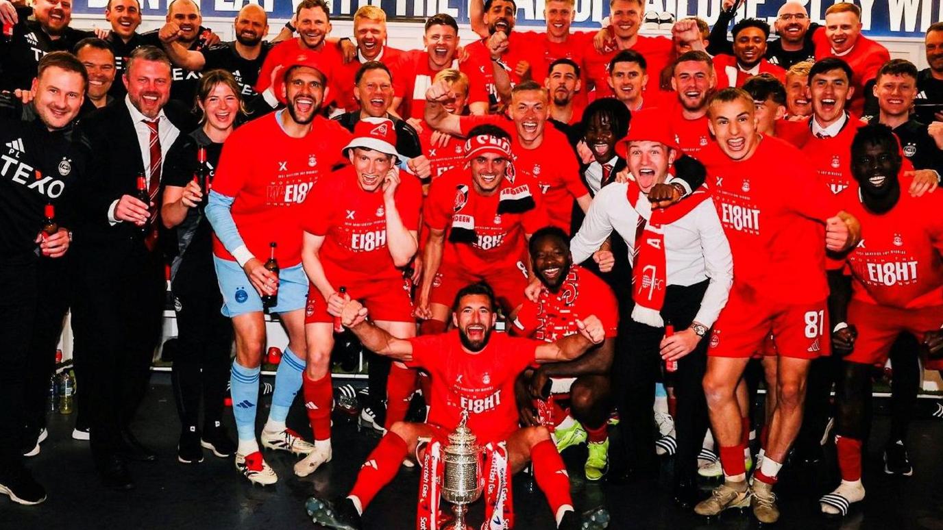 Aberdeen players celebrating with trophy.
