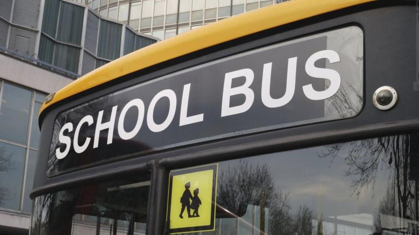 Front of a yellow bus with "school bus" showing above the window