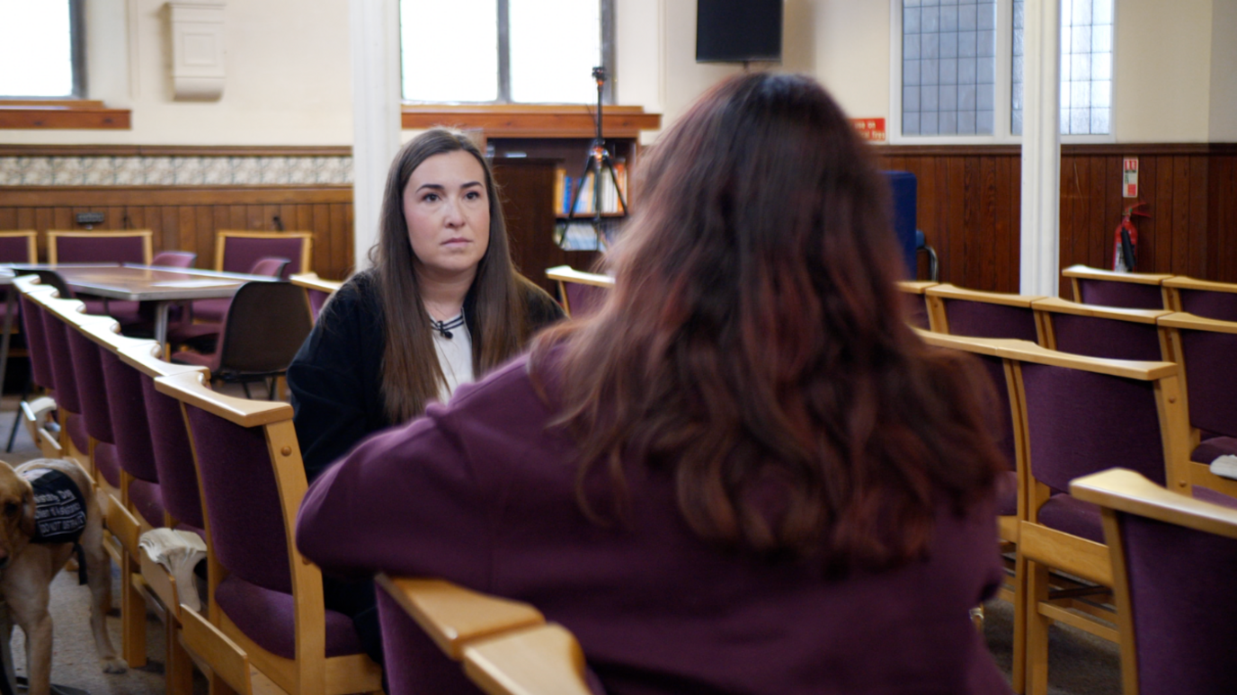 'Jane' sat with her back to the camera in front of reporter Josie Hannett, sat in a church