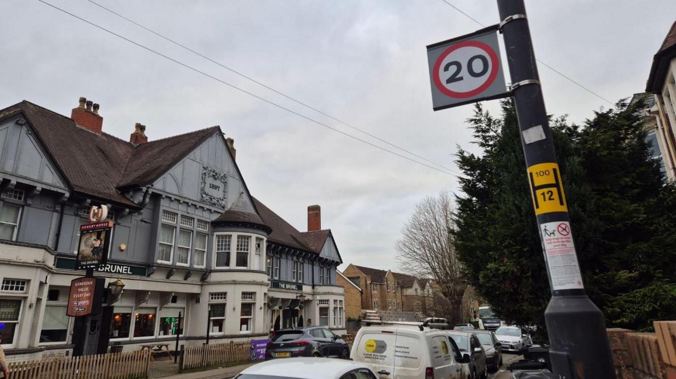 A 20mph sign attached to  a lamp post St John's Lane opposite the Brunel Pub.