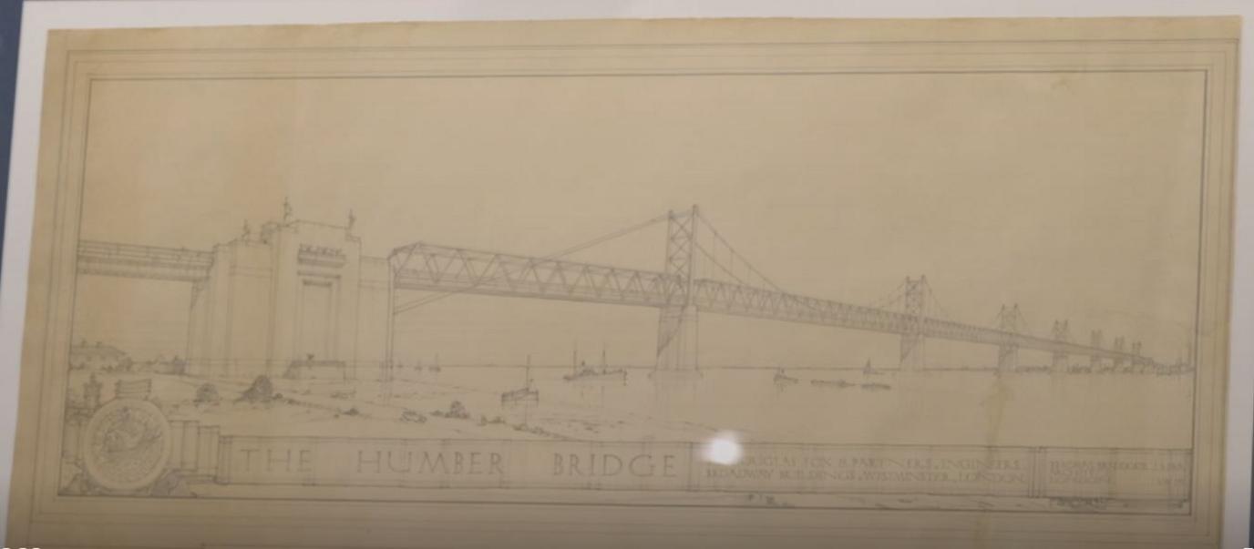 The repaired monochrome drawing of the Humber Bridge. It shows a suspension bridge with steel girders and seven towers spanning a large river estuary with ships passing beneath it.