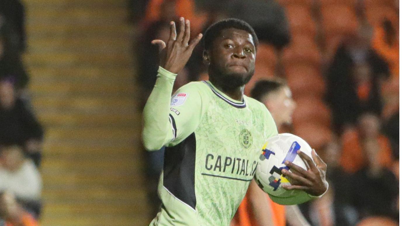 Gideon Kodua, holding the match ball, salutes the Luton fans after scoring against Blackpool