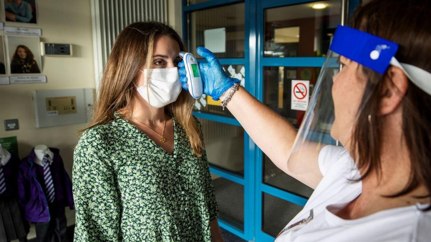 Teacher Catherine McClean has her temperature checked by assistant teacher Hilary Brennan at St Clare's Primary School in Belfast at the start of the new term