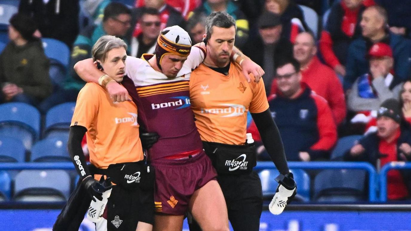 George Flanagan is helped from the field having been injured in Huddersfield's loss to Hull KR on Sunday