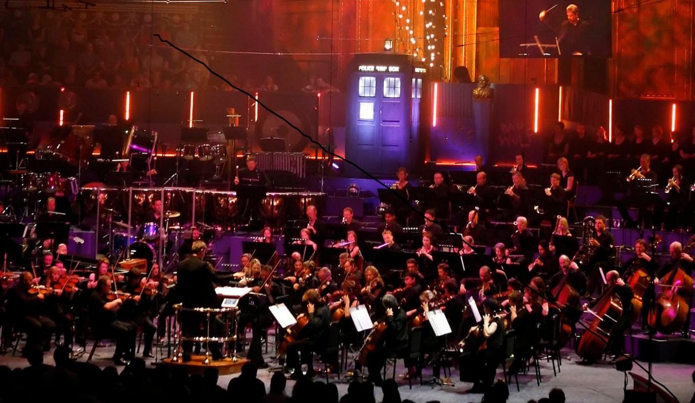 An orchestra with the TARDIS in the background