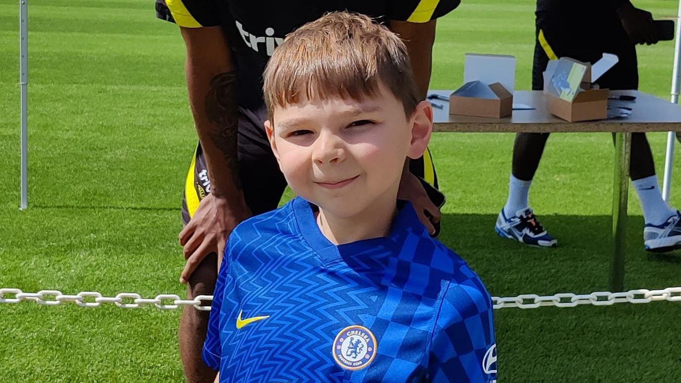 Tony smiling at the camera. He is wearing a blue Chelsea shirt.