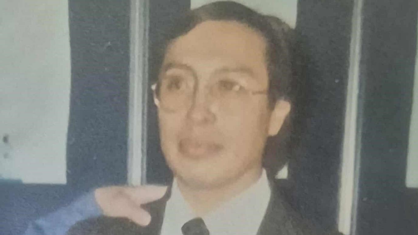 A film photo of Fredi Rivero in a suit wearing glasses.
