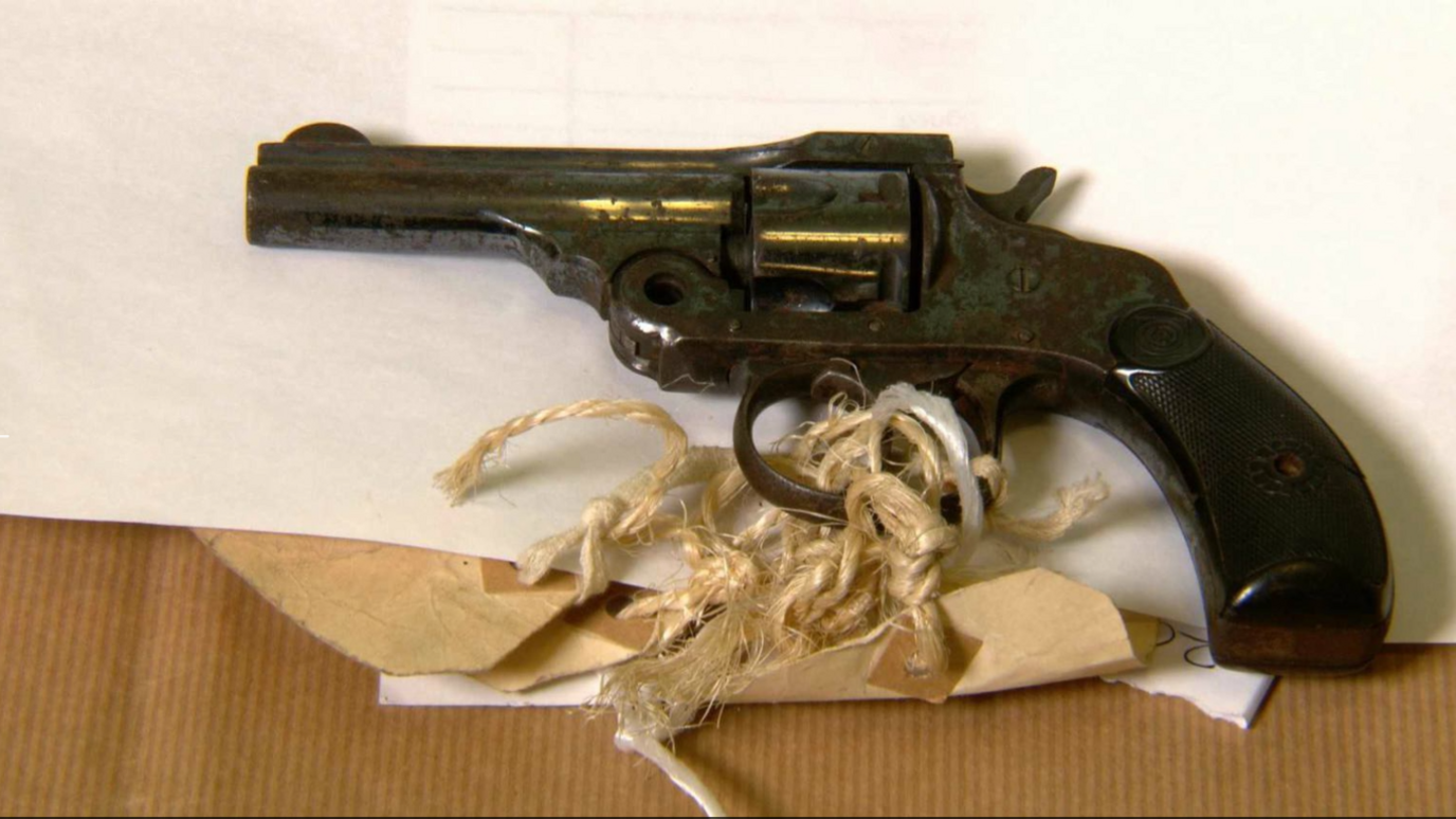 A revolver with a piece of brown paper tied with thread 