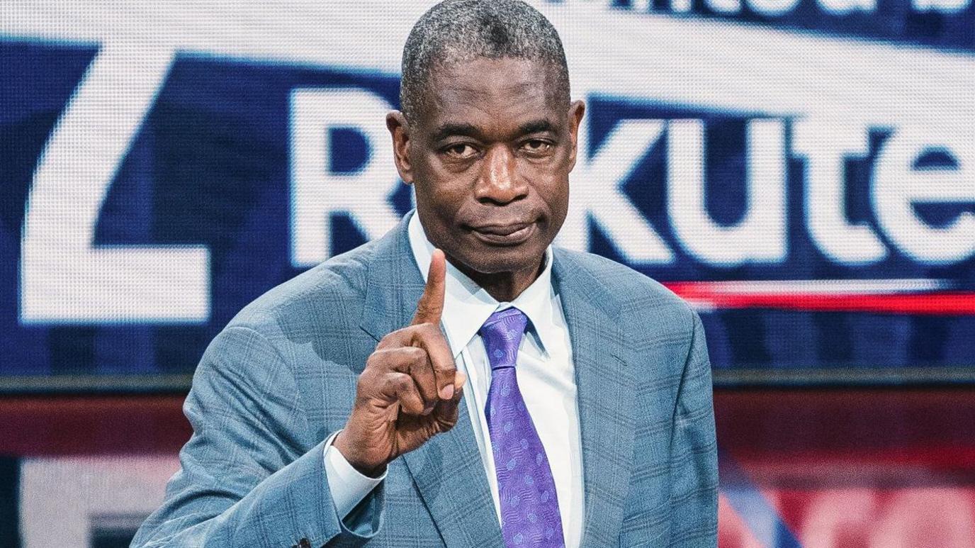 Dikembe Mutombo, wearing a ray bluish suit pinch a purple tie, raises an scale digit towards nan camera