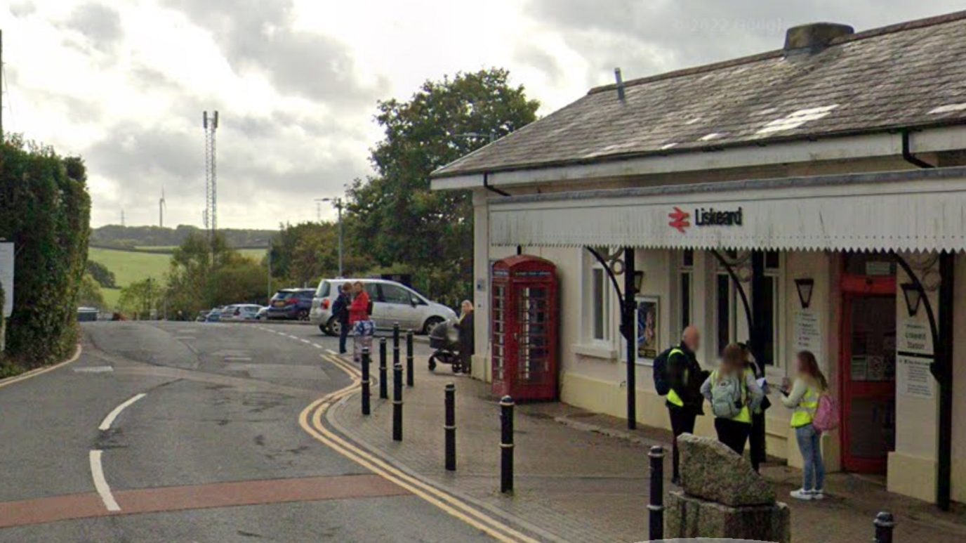 A Google Maps street view of the front of the train station in Liskeard, Cornwall. There are people stood at the entrance of the station.
