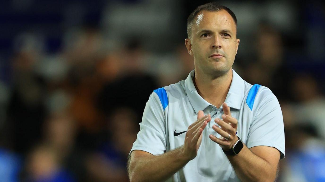 Chris Davies claps the Birmingham City crowd after a game. He is wearing a light coloured club polo shirt
