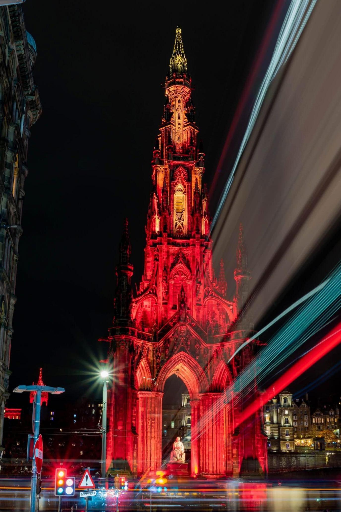 An image of the Scott Monument in Edinburgh, lit up red at night.