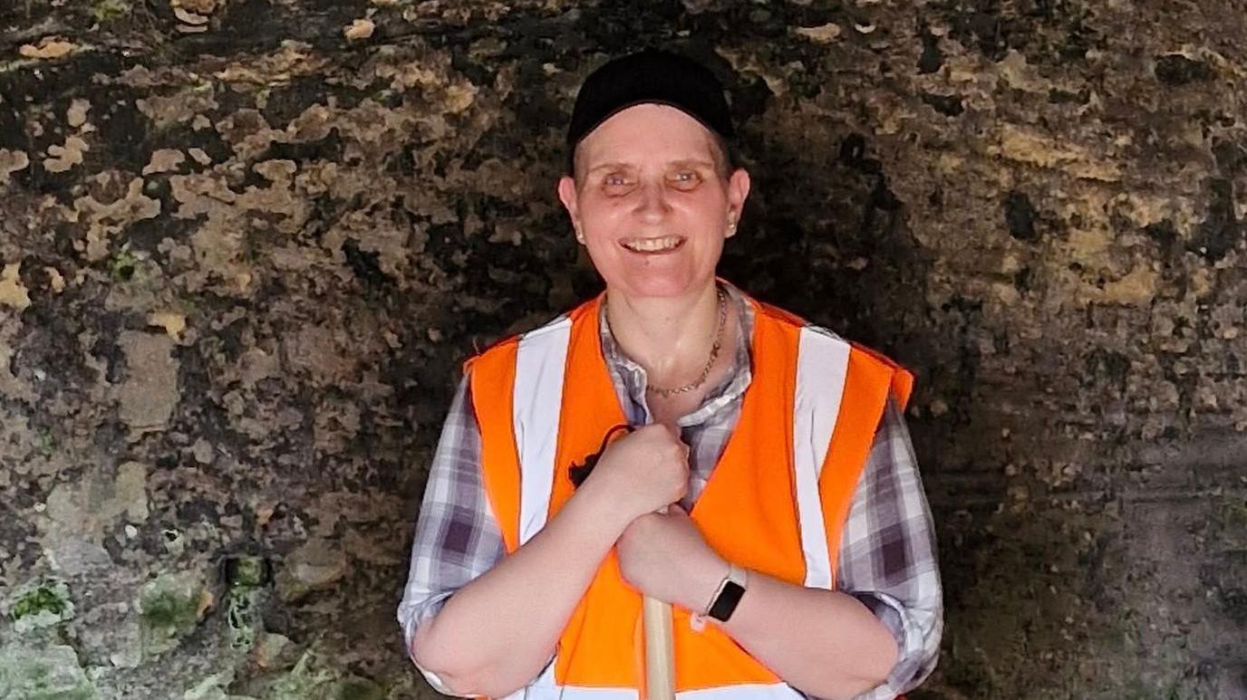 Janine Tanner, inside one of the caves, wearing a hi-vis jacket, smiling at the camera
