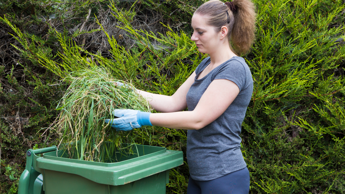 woman using green wheelie bin