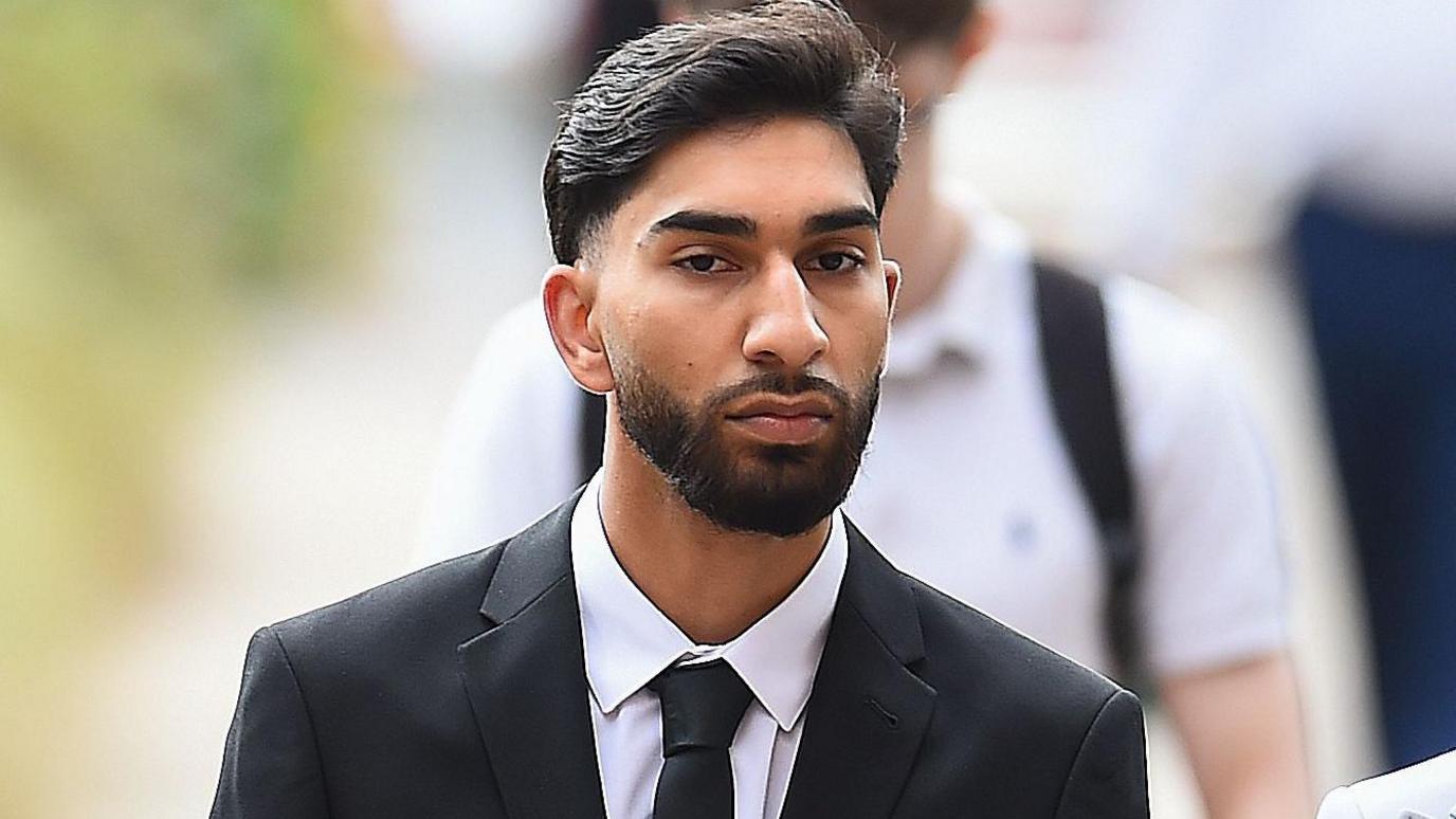 Mohammed Amaaz with black hair and beard and wearing a black suit arrives at Liverpool Crown Court.