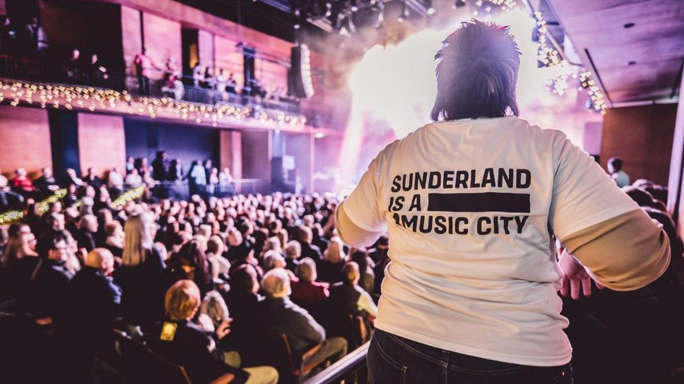 A music fan wearing a Sunderland Music City white T-shirt enjoys a sold out show at The Fire Station in Sunderland. 