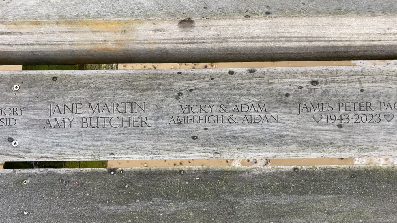 A closer view of some of the names that have been engraved into a grey wooden boards.