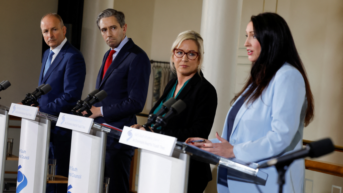 From left to right, Micheál Martin, Simon Harris, Michelle O'Neill and Emma Little-Pengelly stand behind podiums. 