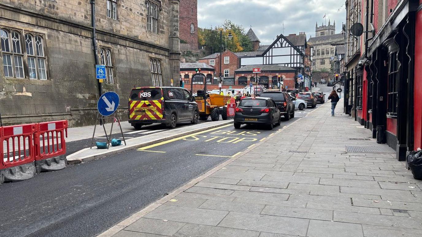 A picture of the floating bus stop on Castle Foregate looking up to the railway station. A central reservation sits in the road with a van and digger in the left lane.