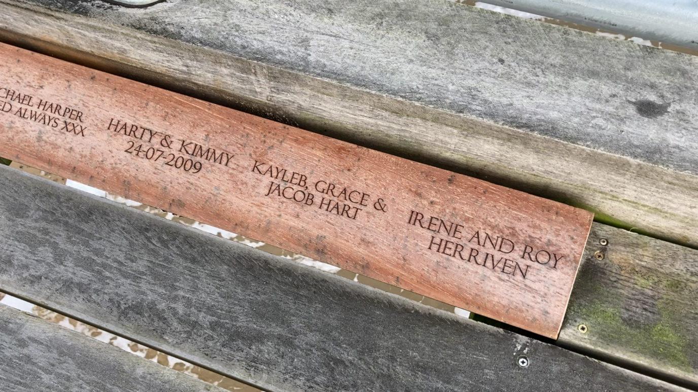 A view of one of the engraved boards that lines the pier edge. A number of names can be seen next to each other on the brown coloured board.