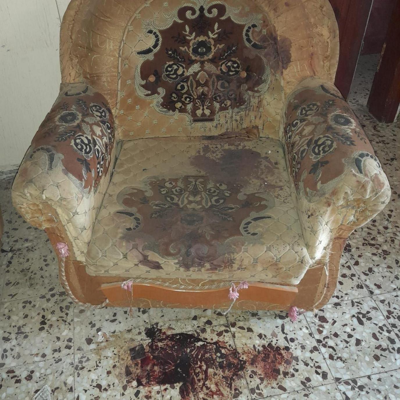 Armchair with blood stains and blood on the floor beneath it