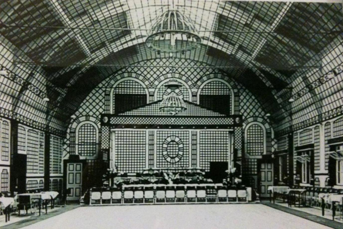 A vintage photograph of the pavilion's hall. The walls are decorated with a cross hatch-like pattern. 