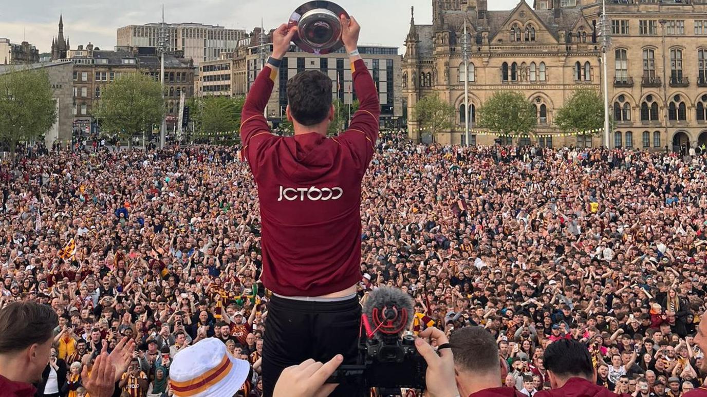 Captain Richie Smallwood with promotion shield in front of fans