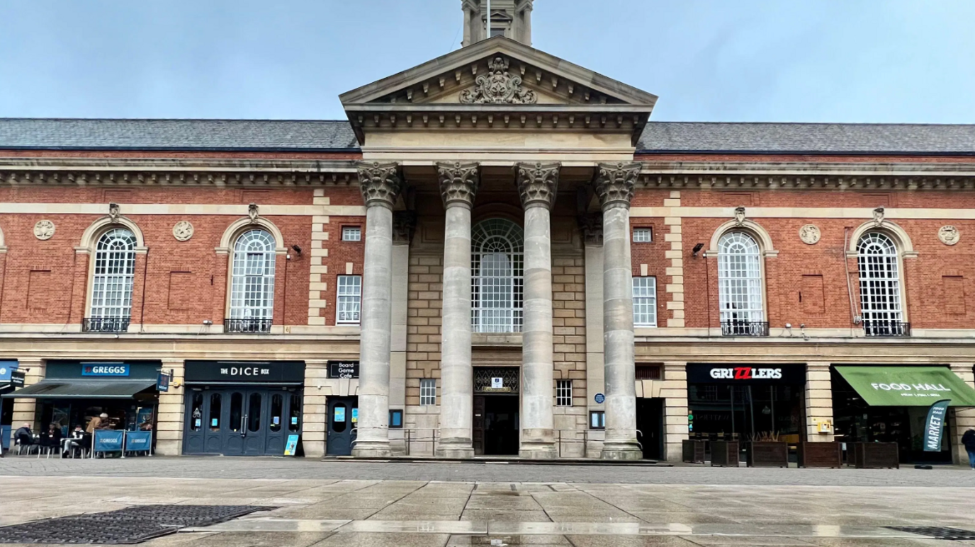 Peterborough City Council's entrance is in the middle. The building is made up of red bricks, and has pillars outside. 