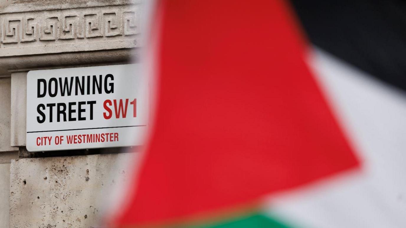  A Palestinian flag flies in front of a road sign reading Downing Street, SW1