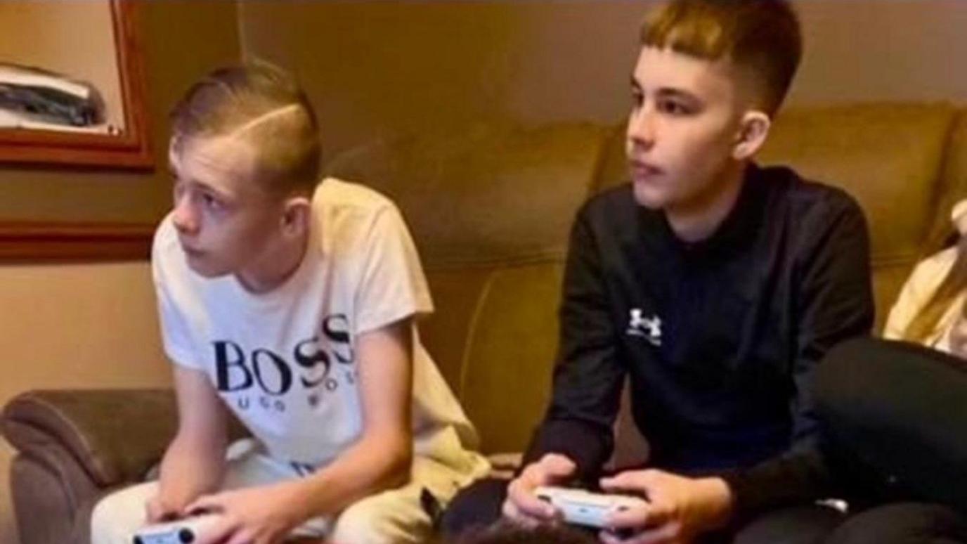 Mason Rist (left) and Max Dixon (right) playing computer games on the sofa