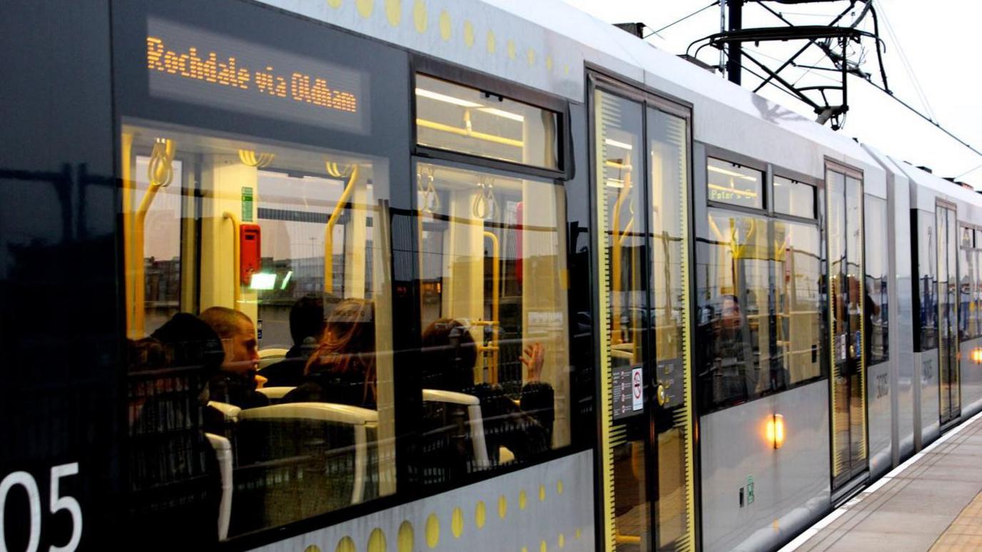 A Metrolink tram bound for Rochdale arriving at a tram stop in central Manchester.