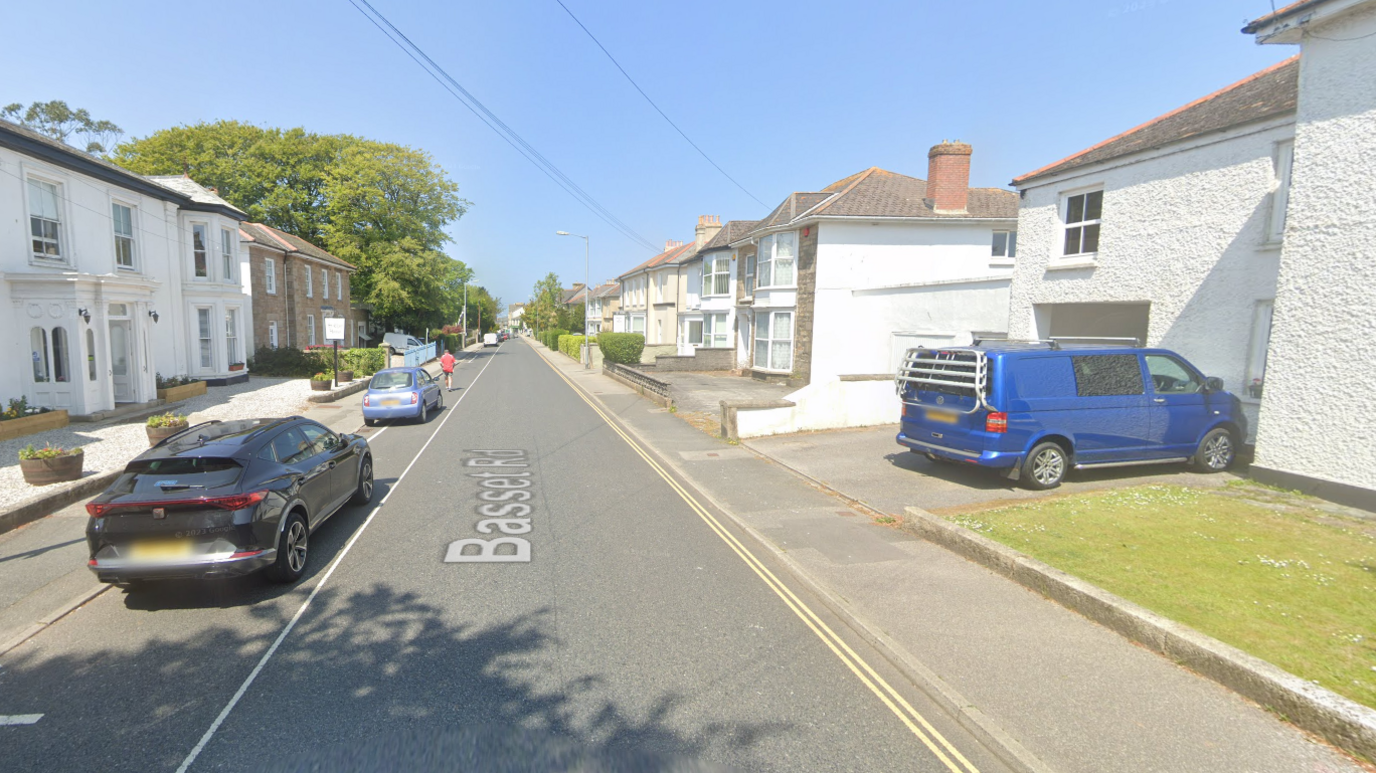 A Google street view Basset Road, Camborne. It's a long road with multiple houses and cars throughout.