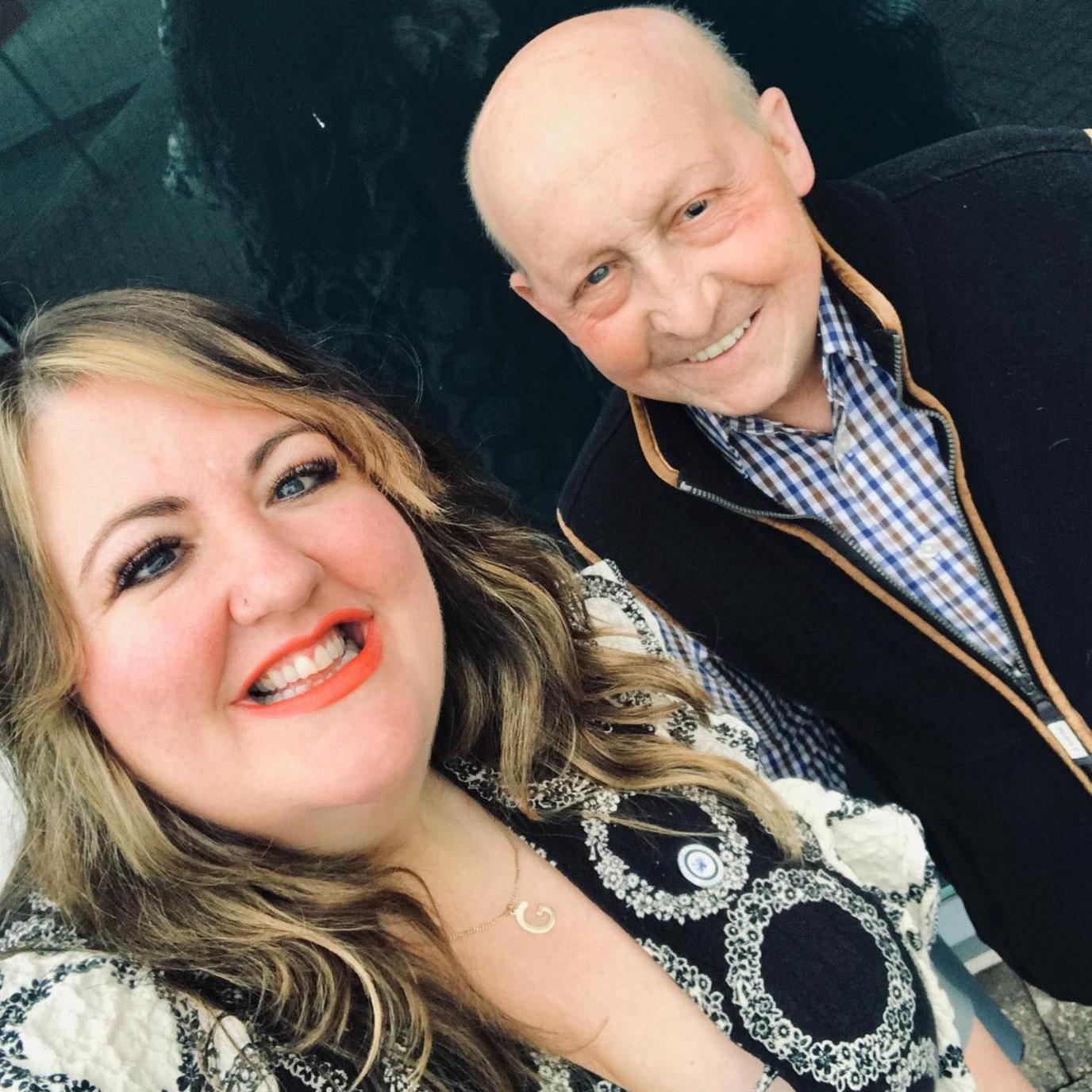 Gini Hackett on the left with highlighted hair and black and white dress. She is smiling at the camera. To her right is Glen Edwards wearing a checked shirt also smiling at the camera.