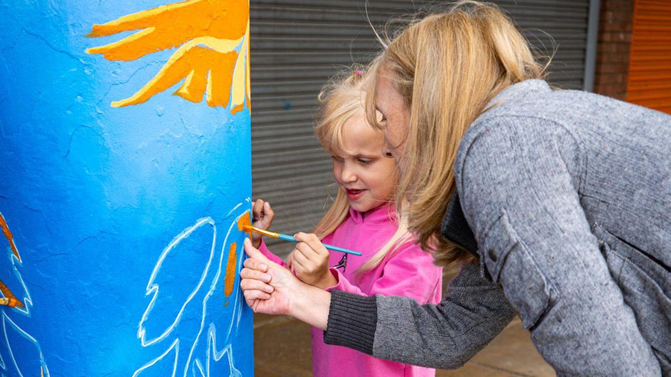 A child and woman painting a pillar in Farley Hill, Luton