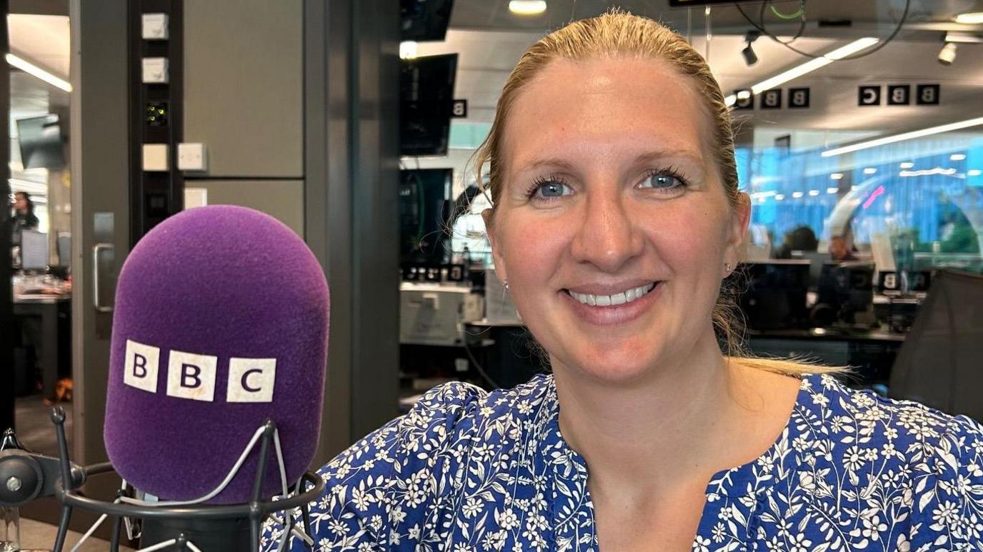 Rebecca Adlington smiles in a radio booth next to a purple BBC microphone