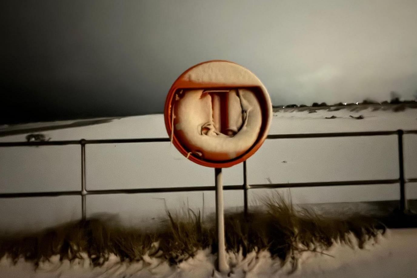 Snow covers a lifesaving ring and the beach beyond at Nairn.