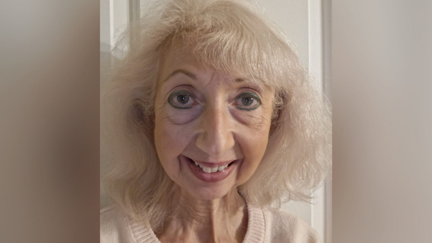 Diana Mulrain, who has white hair, smiles in a selfie