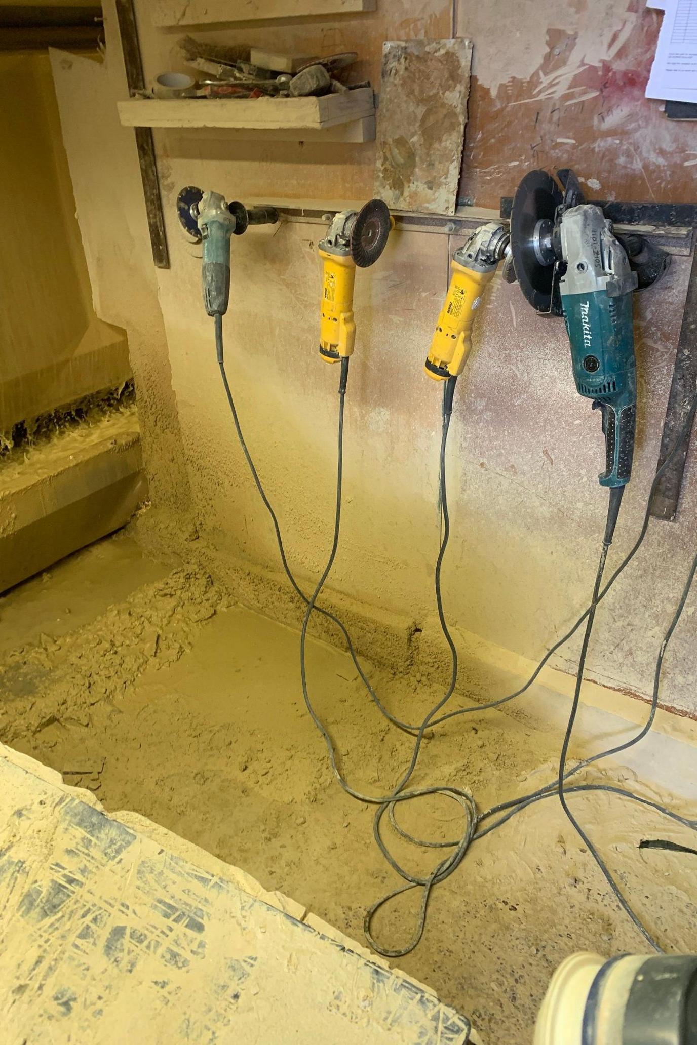 Several tools are hanging on a work shelf with dust particles visible on the floor, which is entirely covered by the substance. 