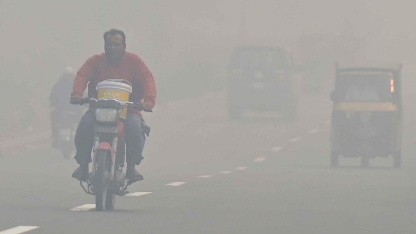 A man rides a bike amid heavy smog in Lahore, Pakistan