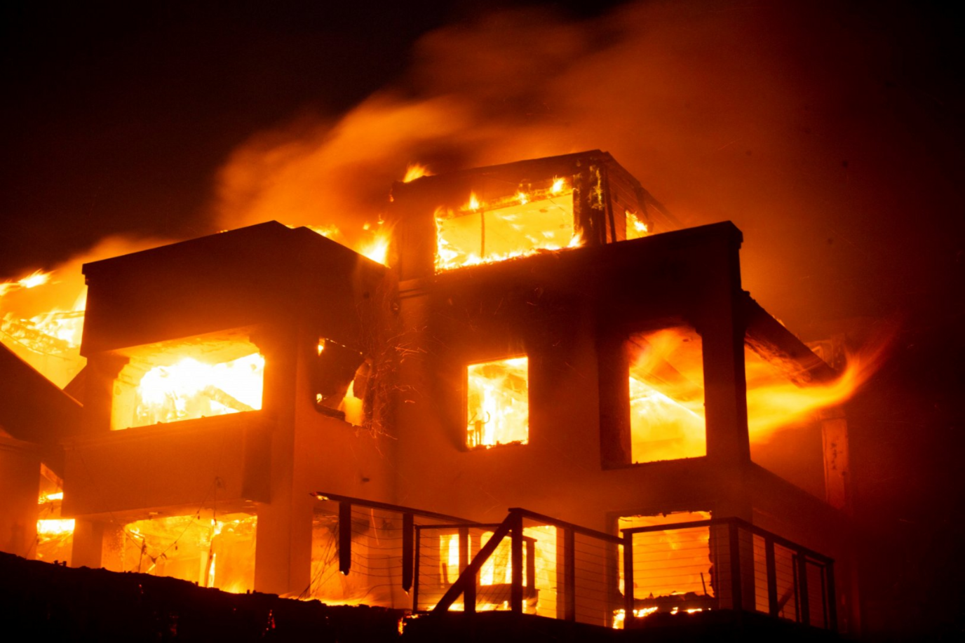 Flames rise from a structure as the Palisades fire burns during a windstorm on the west side of Los Angeles