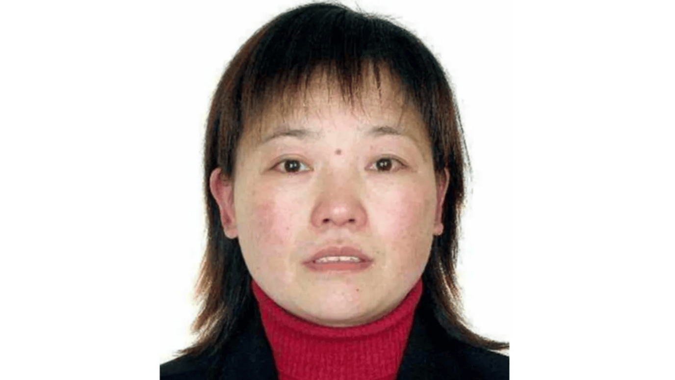 A passport-style photo of Hu Youping. She has shoulder length brown hair and is wearing a red turtle neck jumper and a black jacket.